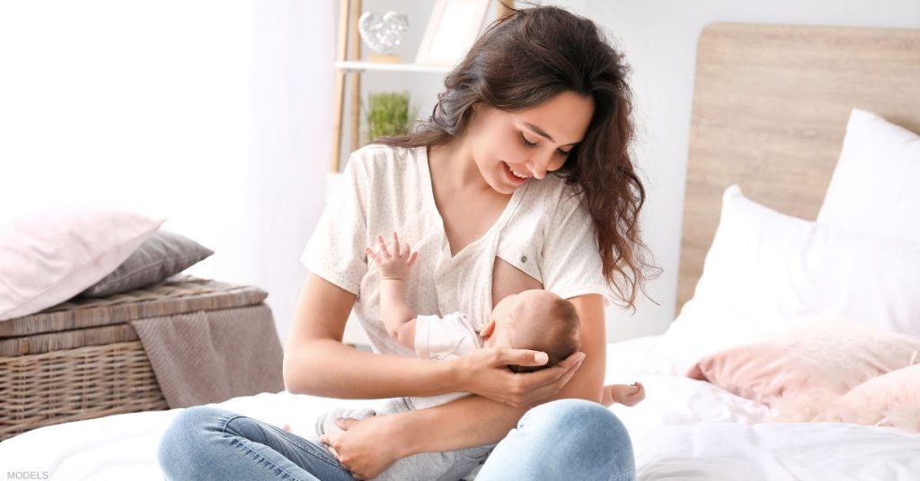 Woman breastfeeding a baby on a bed (MODELS).
