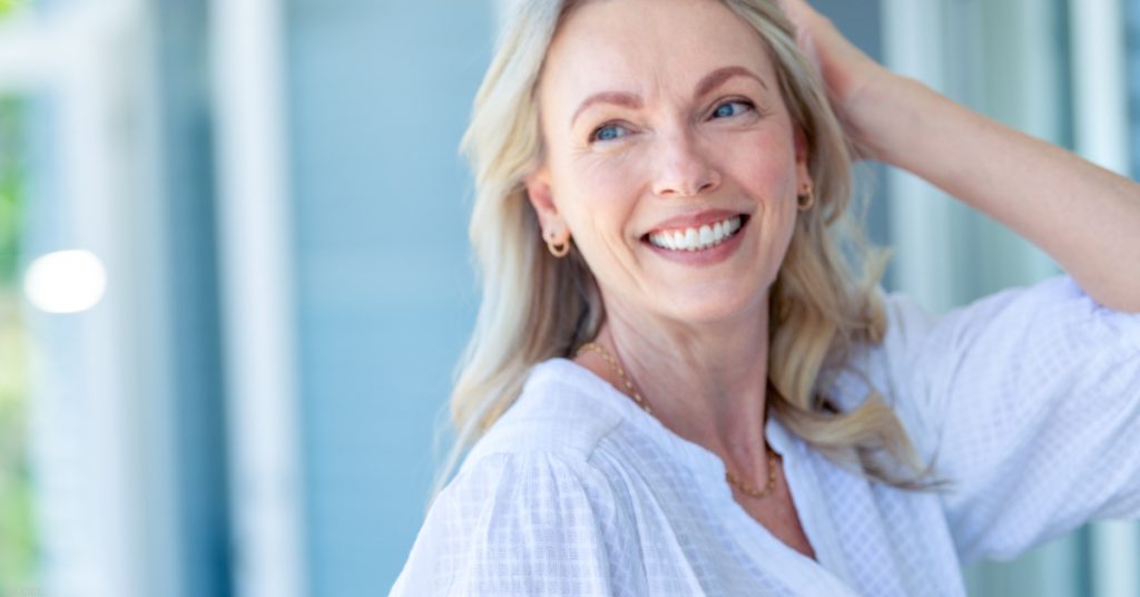 a smiling woman in a white shirt standing in front of a house (MODEL)